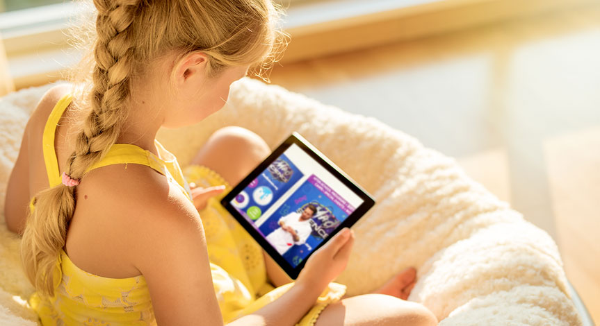 Girl sitting holding an ipad while watching a mad science virtual learning class