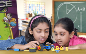 2 girls building a toy car with 2 wheels.