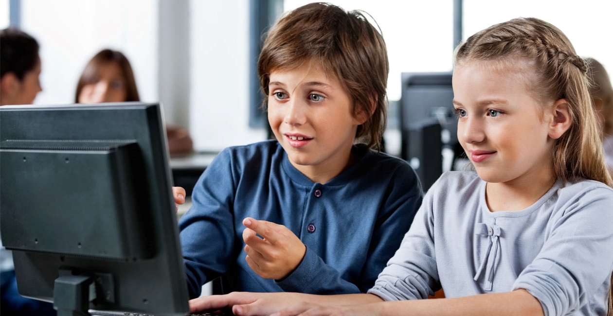 A boy and a girl studying while looking at a computer